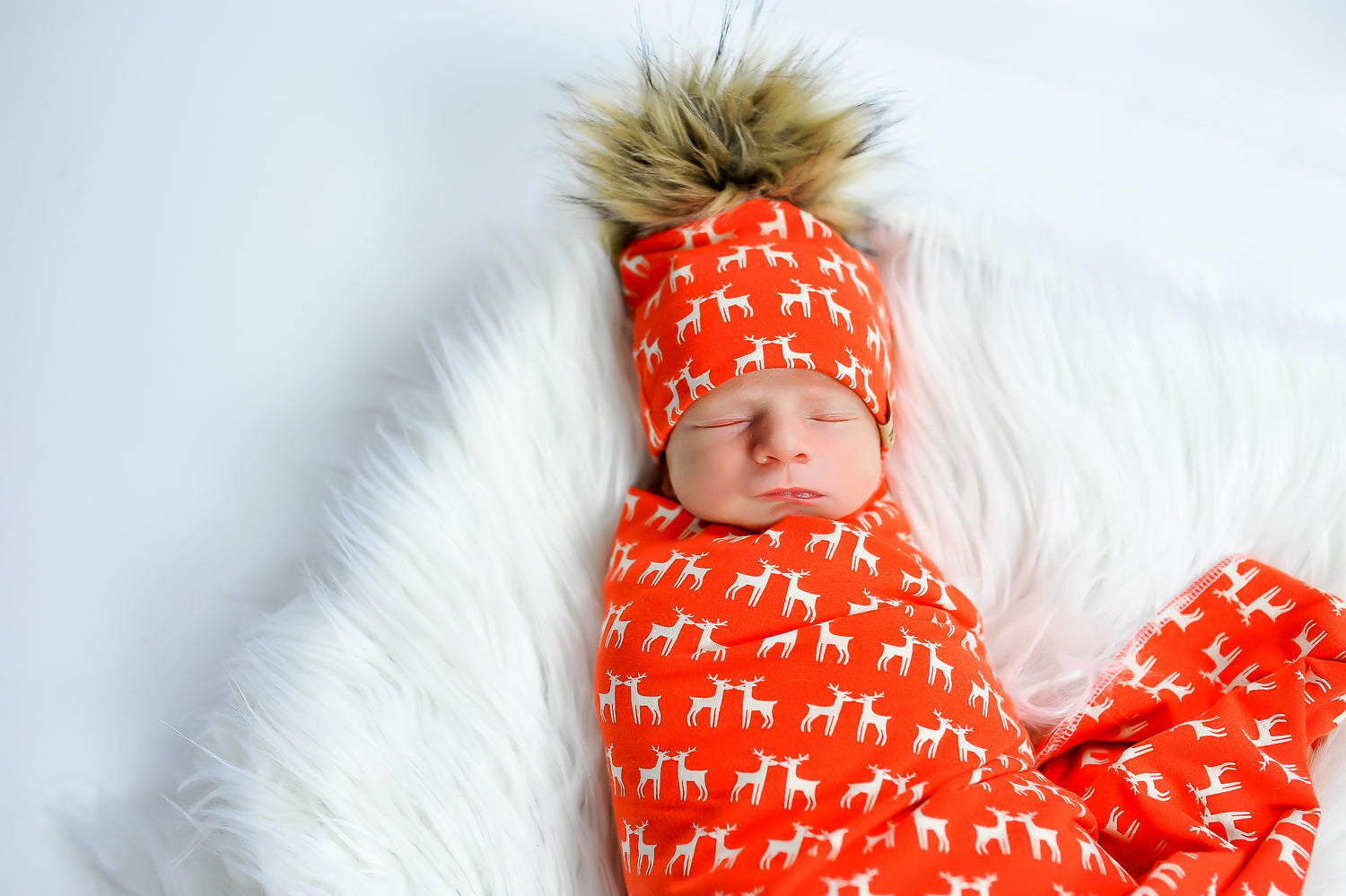 newborn baby wrapped up in a christmas swaddle and matching beanie