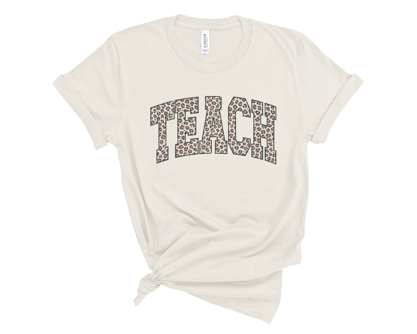An off-white short-sleeve t-shirt with the word 'TEACH' printed across the chest in a leopard print pattern. The t-shirt is styled with a knot at the bottom hem and is photographed flat against a solid white background.